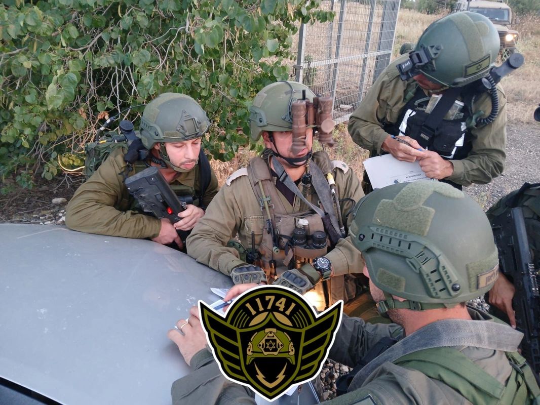Soldiers in tactical gear consulting maps during an operation